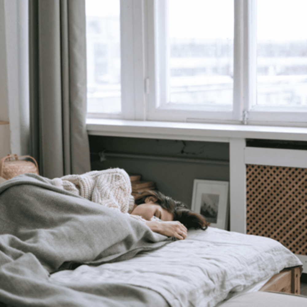Young woman laying on bed under blanket
