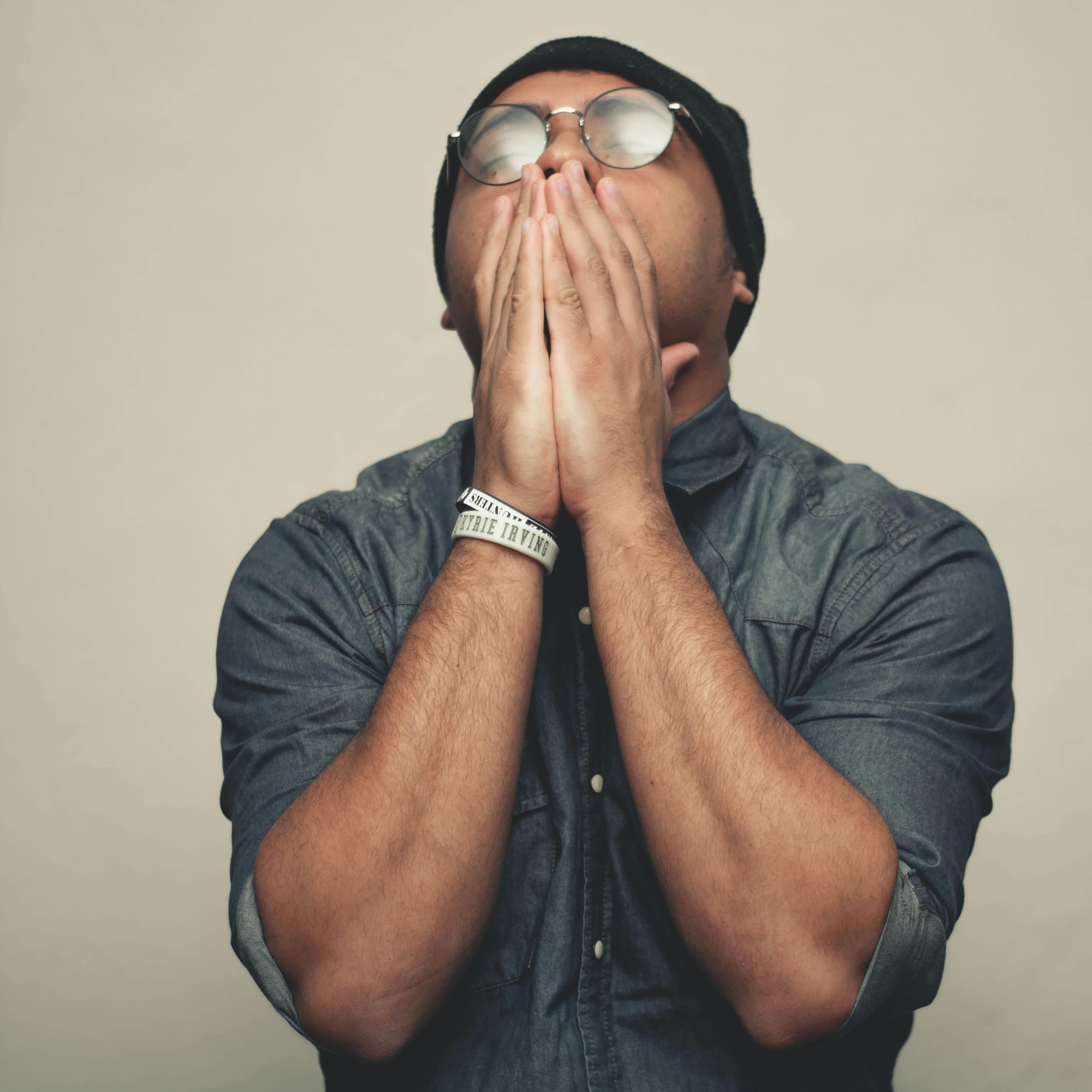 Young man with hands on his mouth looking up