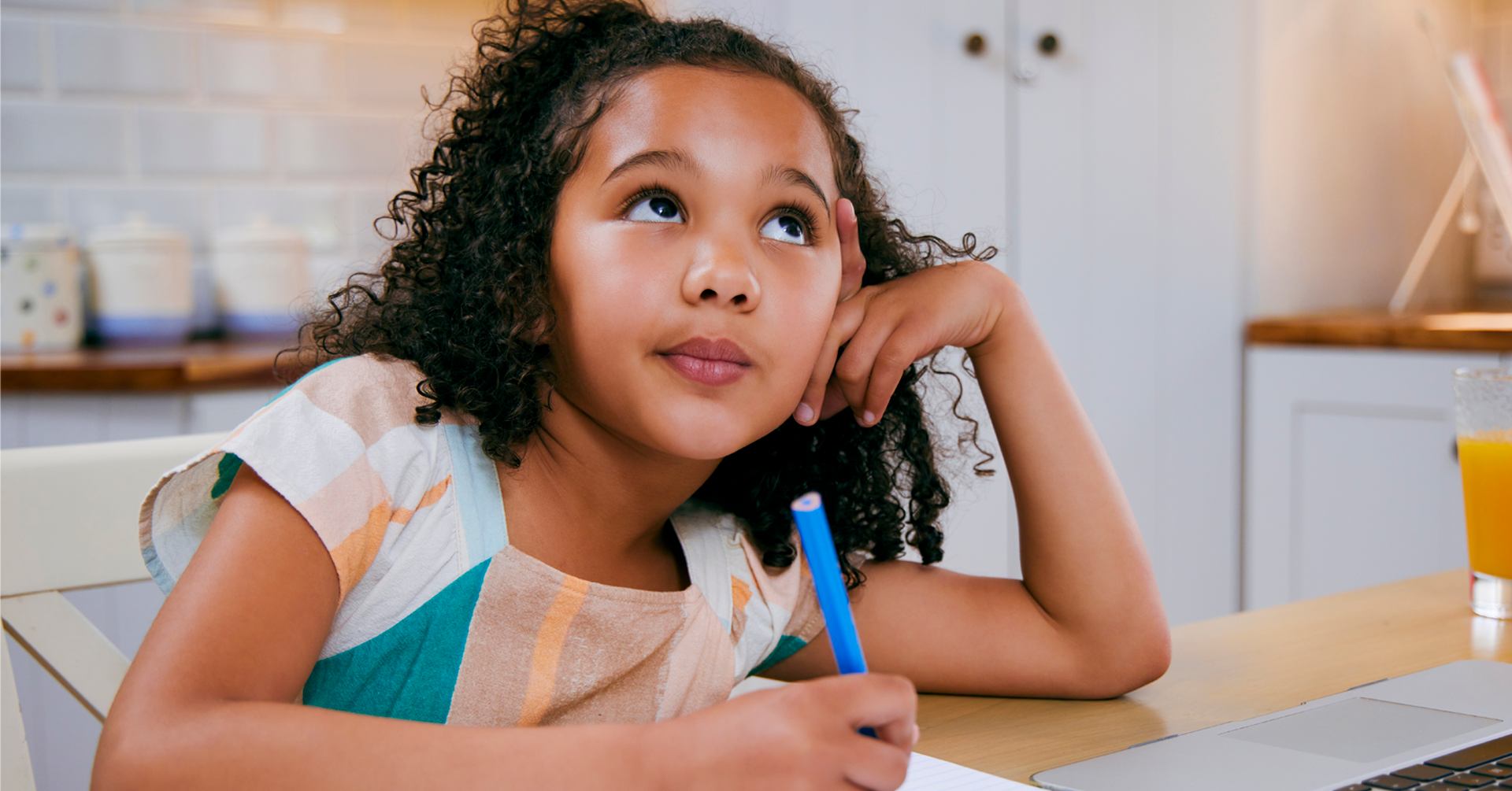 child thinking and writing at a school desk