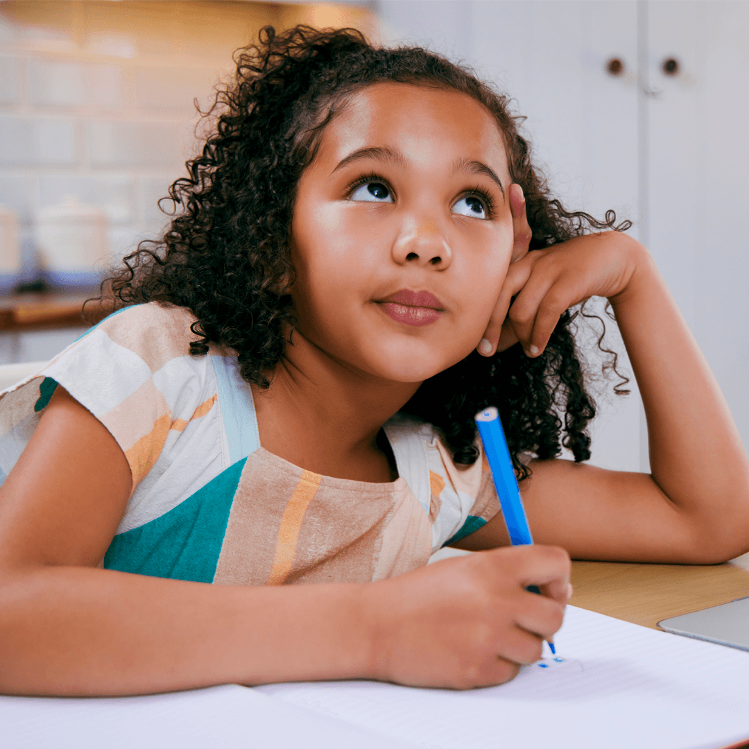 child writing and thinking at school desk