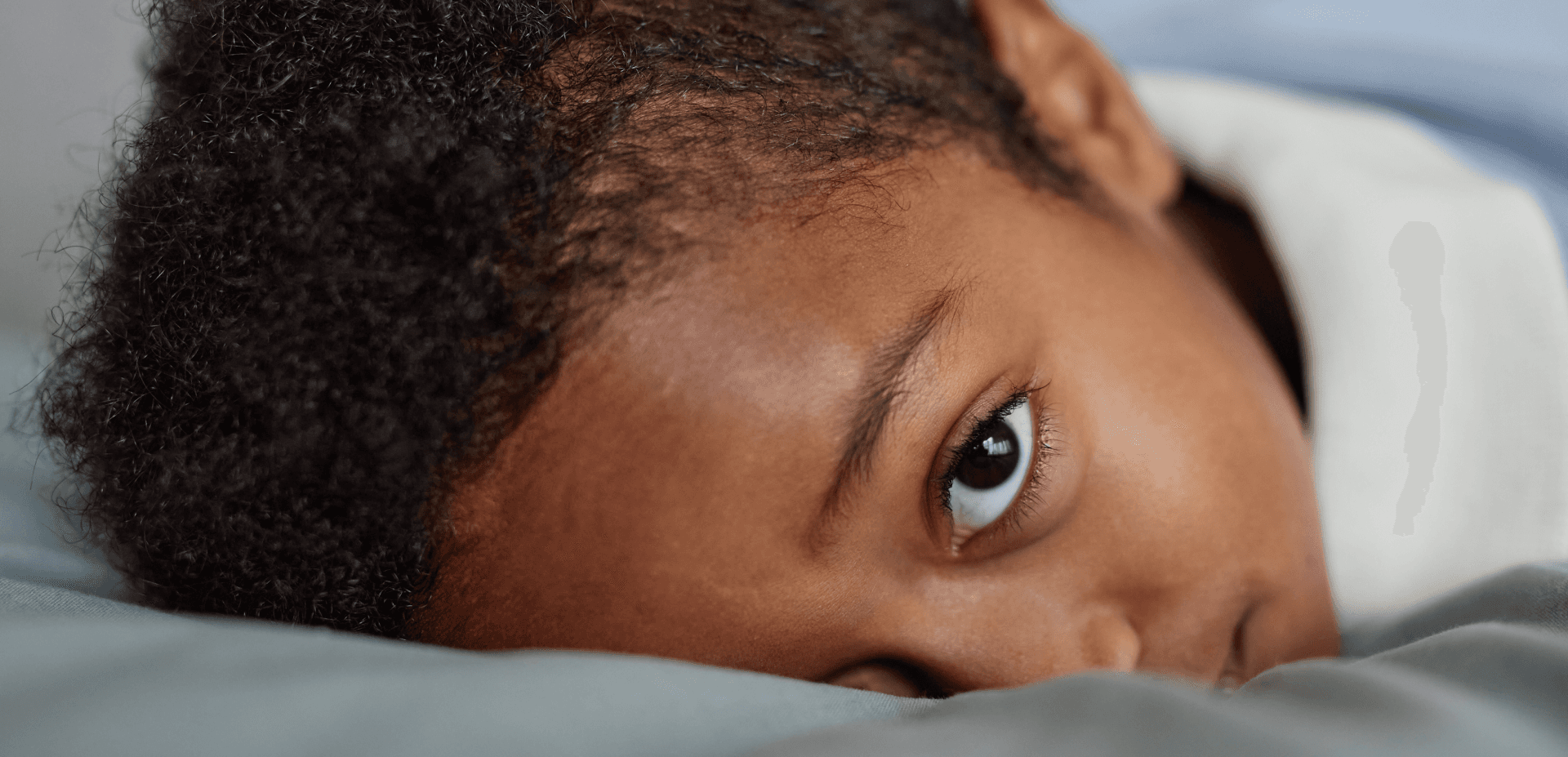 Young boy laying down on a soft surface and looking up at the camera
